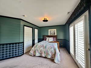 Bedroom with a wainscoted wall, carpet floors, and crown molding and deck and bathroom access