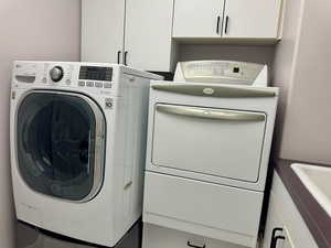Laundry room with independent washer and dryer and cabinet space conveniently located next to primary bedroom