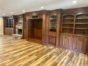 Huge family room featuring light wood-style floors, a fireplace, a textured ceiling, and recessed lighting with elegant built in cabinets