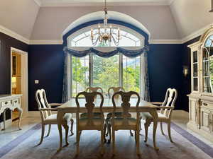 Stunning formal dining space with lofted ceiling, a chandelier, and ornamental molding