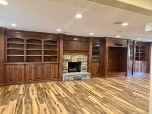 Stunning family room with light wood finished floors, a stone fireplace, and recessed lighting