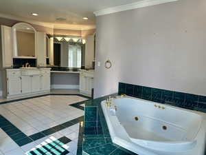 Full primary bath with ornamental molding, a whirlpool tub, vanity, tile patterned flooring, and recessed lighting