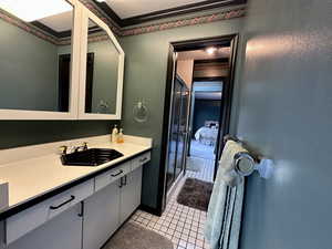 Bathroom with tile patterned floors, vanity, and ornamental molding