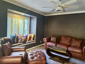 Carpeted den featuring a window seat, a ceiling fan and ornamental molding