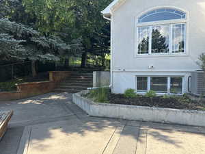 View of side of property featuring stucco siding, stairway, and a patio area