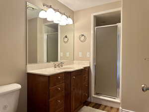 Bathroom with vanity, a stall shower, and wood finished floors