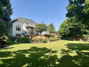 Back view of home with grassy yard with a balcony