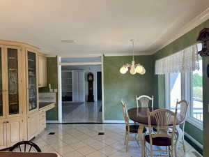 Informal dining room featuring a beautiful built-in hutch, light tile patterned floors, a chandelier, and crown molding
