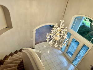 Tiled foyer featuring a high ceiling, beautiful etched glass door, arched walkways, and an elegant chandelier