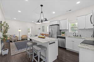 Kitchen with dark wood finished floors, a center island, open floor plan, decorative backsplash, and recessed lighting