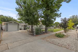 View of front facade featuring concrete driveway, a detached garage, and a gate