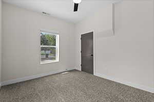 Carpeted empty room featuring a ceiling fan and baseboards