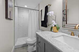 Full bathroom with vanity, tiled shower, and tile patterned floors