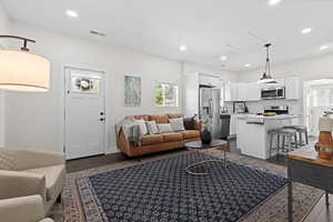 Living area with dark wood-type flooring and recessed lighting