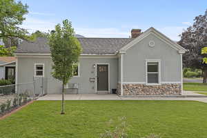View of front of house with stucco siding, roof with shingles, a chimney, and a patio