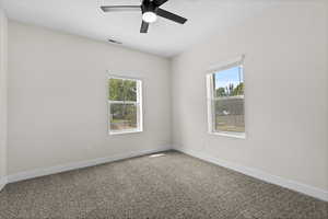Carpeted empty room featuring plenty of natural light and a ceiling fan
