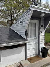 View of exterior entry featuring roof with shingles