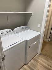 Washroom with separate washer and dryer and light wood-type flooring