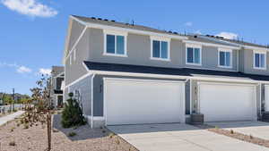 View of front facade featuring an attached garage, driveway, and roof with shingles