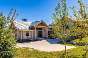View of front of property with a standing seam roof, a metal roof, board and batten siding, a patio, and a front lawn