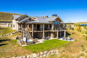 Rear view of property with a patio, stairway, an outdoor fire pit, stone siding, and board and batten siding