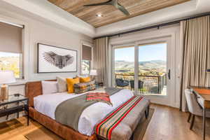 Bedroom with a tray ceiling, wood ceiling, access to outside, multiple windows, and recessed lighting