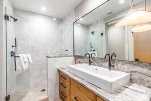 Full bath with tile walls, a stall shower, and vanity
