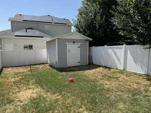 Fenced backyard featuring a storage shed