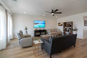 Living room with ceiling fan, recessed lighting, and light wood finished floors