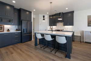 Kitchen featuring high end refrigerator, tasteful backsplash, a kitchen breakfast bar, dark wood-type flooring, and recessed lighting