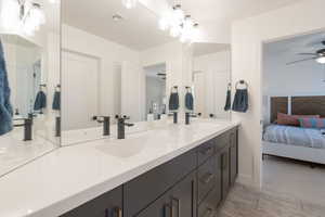 Full bathroom with double vanity, ensuite bath, and ceiling fan