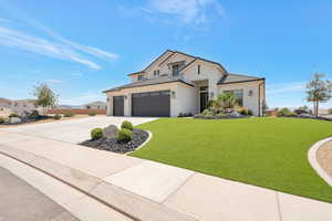 View of front of house featuring a front lawn, a garage, driveway, stucco siding, and a tiled roof