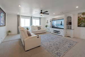 Living area featuring light colored carpet, a ceiling fan, and recessed lighting