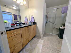 Bathroom featuring vanity, tile patterned floors, and a stall shower