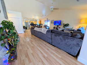 Living room featuring light wood-style floors, ceiling fan, and vaulted ceiling