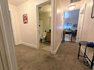 Corridor with carpet floors and vaulted ceiling