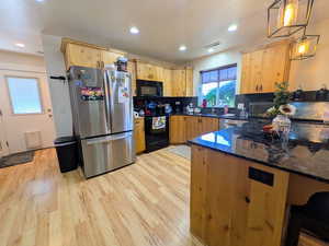 Kitchen with black appliances, dark stone counters, light brown cabinetry, decorative backsplash, and recessed lighting