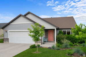 View of front of property with a garage, board and batten siding, driveway, a front yard, and roof with shingles