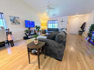 Living room featuring a ceiling fan, light wood-style flooring, and lofted ceiling