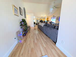 Living area with light wood-type flooring, a ceiling fan, and vaulted ceiling