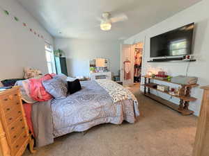 Carpeted bedroom with a spacious closet and a ceiling fan