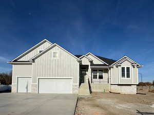 View of front of house featuring board and batten siding, stone siding, and driveway