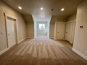 Additional living space with a textured ceiling, light colored carpet, and recessed lighting