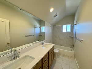 Bathroom with double vanity, light marble finish floors, washtub / shower combination, vaulted ceiling, and healthy amount of natural light