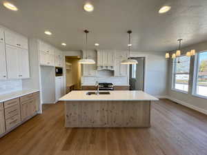 Kitchen featuring white cabinetry, a textured ceiling, plenty of natural light, recessed lighting, and light wood-style flooring