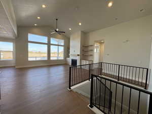 Unfurnished living room featuring wood finished floors, lofted ceiling, a fireplace, a ceiling fan, and recessed lighting