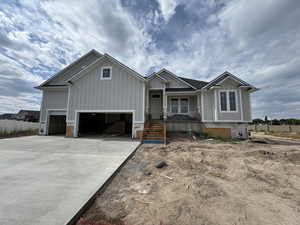 View of front facade featuring board and batten siding, a garage, covered porch, and driveway