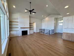Unfurnished living room with recessed lighting, a fireplace, light wood-style floors, lofted ceiling, and a ceiling fan