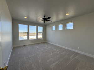 Empty room featuring a textured ceiling, plenty of natural light, carpet floors, a ceiling fan, and recessed lighting