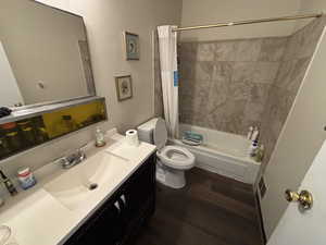Full bath with wood finished floors, shower / tub combo with curtain, and vanity